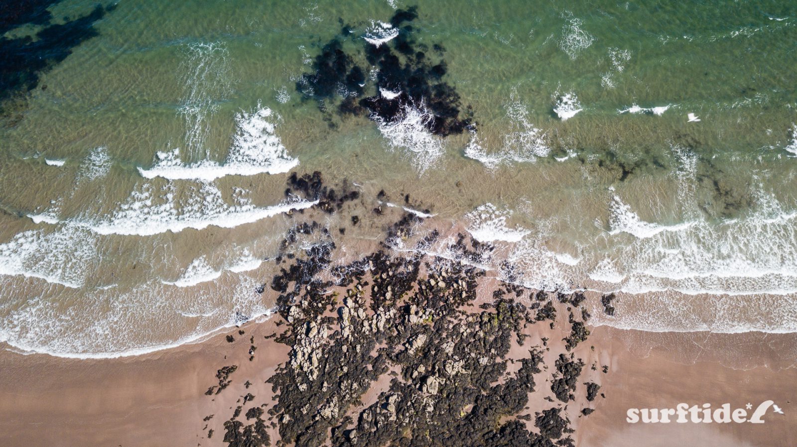 Aerial view of waves crashing in on the rocky beach at Macharioch in Argyll, Scotland