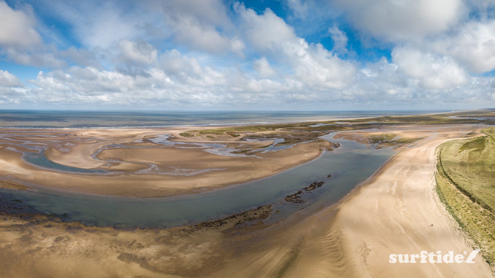 Aerial photo of Brancaster beach at low tide showing the vast expanse of sand and water draining back into the sea