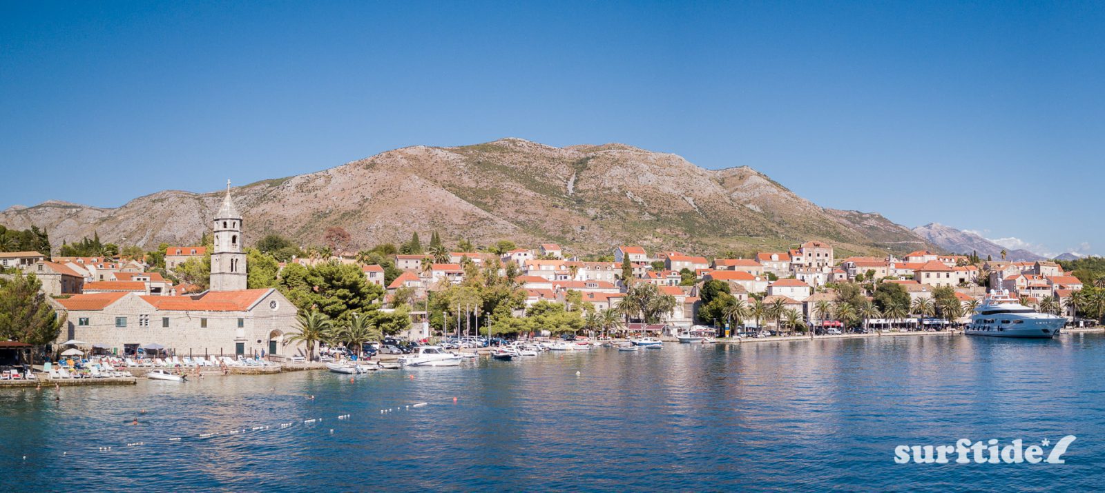 Panoramic photo showing the historic architecture, blue sea and boats in Cavtat harbour in southern Croatia