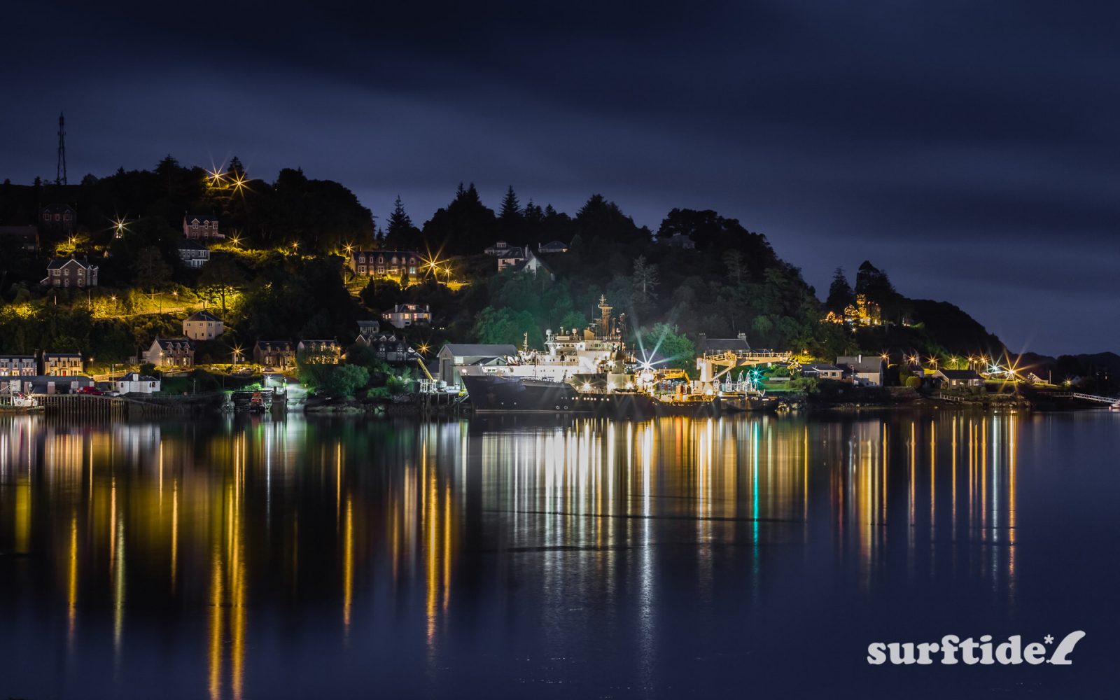 Long exposure night photo of boats and light reflecting off the water in Oban harbour, Scotland